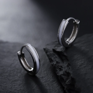 Silver hoop earrings with white enamel finish on black stone background for men and women