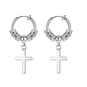 Macro shot of silver gothic cross earrings with intricate dragon texture details