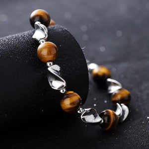 Tiger eye bead bracelet with silver twisted metal links on a premium black jewelry stand