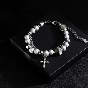 Titanium steel beaded bracelet with cross pendant and heart charms on black pedestal