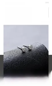 Macro shot of silver round titanium steel stud earrings with etched leaf vein texture