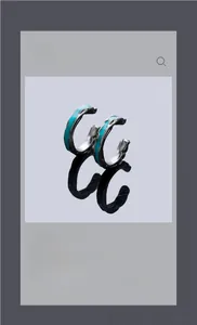 Macro shot of silver C-shaped clip earrings with blue wave-textured enamel inlay