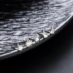 Five-piece silver punk rock gesture earrings set on textured black background