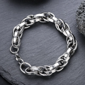 Minimalist silver steel chain bracelet with textured links on a dark rock background