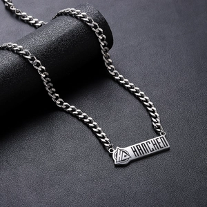 Silver cuban link necklace with rectangular engraved logo tag on black display