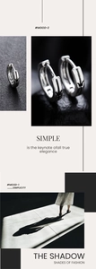 Detailed view of silver huggie earrings with crown engravings on a minimalist mood board