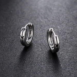 Polished silver punk hoop earrings with black crown engraving on leather background