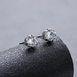 Elegant silver crown setting earrings with round cubic zirconia on a textured display