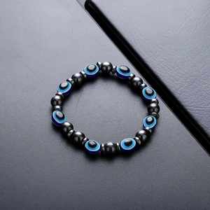 Handmade hematite bead bracelet featuring blue evil eye charms on a dark leather surface