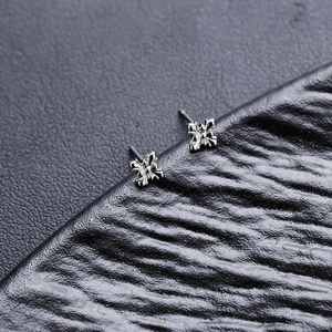 Boucles d'oreilles fleurs en croix argentées avec texture gravée vintage sur fond noir
