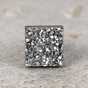 Close-up of square magnetic earring with silver crystal cluster texture and metallic finish