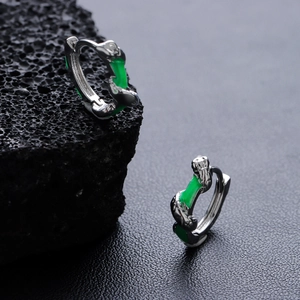 Minimalist silver bamboo hoop earrings with green enamel accents on dark volcanic rock