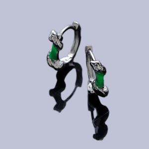 Bamboo-inspired silver hoop earrings with emerald green accents on a dark reflective surface