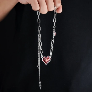 Collier gothique en acier titane avec cœur et croix et bords épineux sur fond noir
