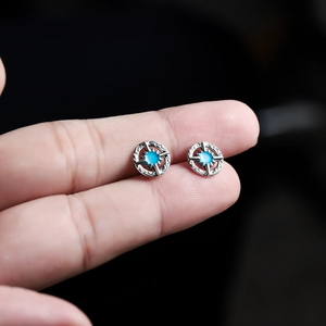 Vintage silver starburst stud earrings with turquoise stone held between fingertips
