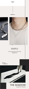 Detail of layered silver feather necklace with sleek rectangular tag and mixed chain styles