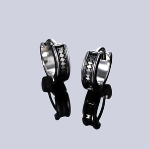 Vintage silver earrings with black woven pattern on a reflective dark grey surface