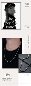 Detail of minimalist cylinder link necklace with silver woven chain on stone background