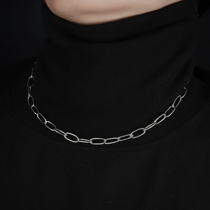 Minimalist stainless steel paperclip chain necklace worn over a black turtleneck top