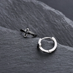 Créoles minimalistes en argent avec motif croix noire sur fond de roche texturée