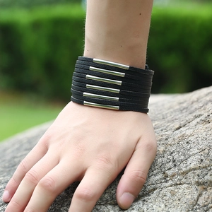 Men's multi-layer black leather bracelet with silver metal tubes on a natural stone background