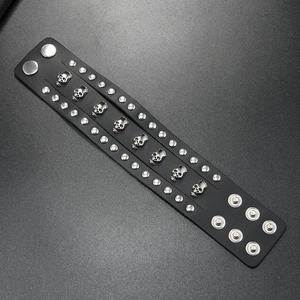 Detail of punk leather bracelet with silver skull charms and double-row metal studs