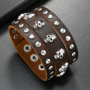 Detail of wide punk leather bracelet featuring skull charms and silver metal studs