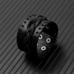 Detail of black woven leather men's punk bracelet with vintage cross-stitch and snap button