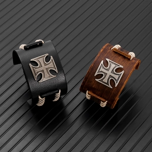 Detail of punk leather bracelets with metal cross emblem and stitched edges