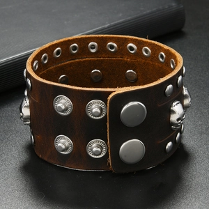 Detail of dark brown punk leather bracelet featuring silver skull charms and studs