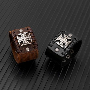 Dettaglio dei bracciali punk in pelle con emblema della croce e rivetti in metallo
