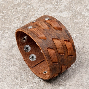 Detail view of vintage brown leather wide cuff bracelet with woven straps and metal snaps