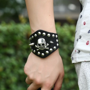 Punk wide leather bracelet featuring a silver skull and sharp metallic rivets on wrist