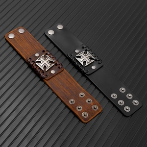 Dettaglio di due bracciali punk in pelle con ciondoli a croce e bottoni a pressione regolabili