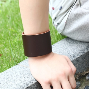 Men's retro dark brown wide leather wristband on a stone step with grass background