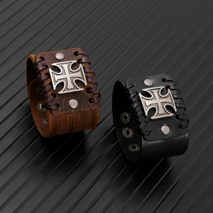 Dettagli di bracciali punk in pelle con croce di ferro vintage e bordi intrecciati