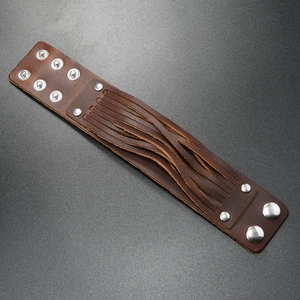 Detail of brown wide leather cuff with silver studs and adjustable metal snap buttons