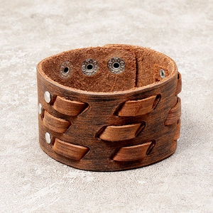 Retro brown leather cuff bracelet with woven texture and metallic studs on stone background