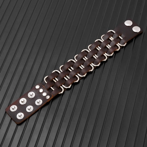 Macro shot of brown leather punk bracelet showing silver metal rings and adjustable snaps
