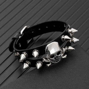 Detail of punk leather bracelet with metal skull and silver-tone spiked rivets