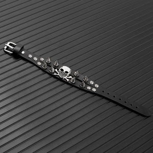 Macro shot of punk black leather bracelet featuring silver metal spikes and skull charm