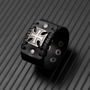 Dettaglio di bracciale punk in pelle con croce metallica e bordi in pelle intrecciata