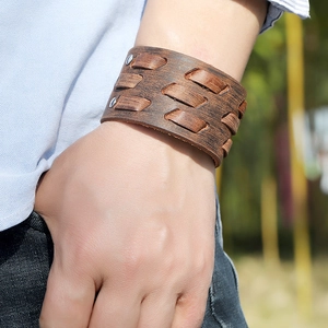 Detail of vintage brown leather wide bracelet with woven strips and metallic rivets