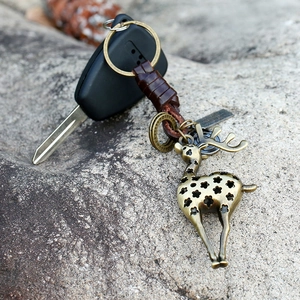 Porte-clés cerf en bronze vintage avec lanière en cuir tressé sur une pierre rustique
