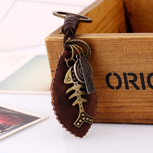Vintage leather keychain with bronze fishbone pendant hanging on a rustic wooden box