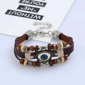 Dettaglio di un bracciale in pelle multistrato con ciondolo malocchio e perline