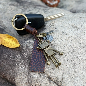 Retro Handgefertigter Leder-Schlüsselanhänger mit Metallroboter auf strukturiertem Stein