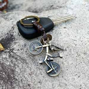 Retro bronze bicycle keychain with brown braided leather strap and engraved metal tag