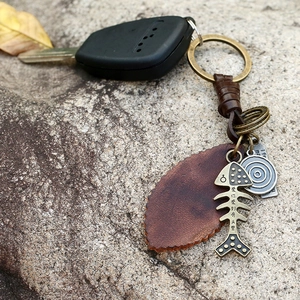 Vintage braided leather keychain featuring bronze fish bone pendant on natural stone background