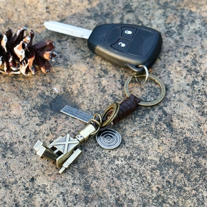 Handcrafted vintage leather robot keychain with movable limbs on a natural stone base